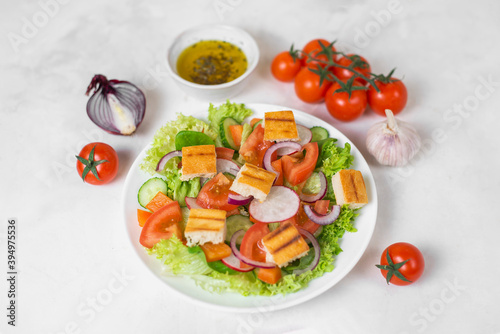 Traditional Middle Eastern vegetarian salad fattoush. Lebanese cuisine recipe. Fresh vegetables, cherry, lettuce, toasted pita bread. White concrete background. Low-calorie, healthy meal, close up. 