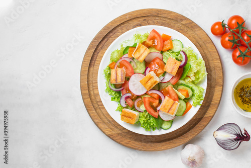 Traditional Middle Eastern vegetarian salad fattoush. Lebanese cuisine recipe. Fresh vegetables, cherry, lettuce, toasted pita bread. White concrete background. Healthy meal, top view. Copy space
