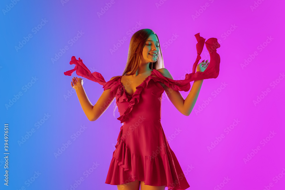 Fototapeta premium Dancing. Half-length portrait of beautiful girl in fashionable, romantic outfit on gradient purple-blue background in neon light. Copyspace for ad. Fashion, beauty, party, disco, emotions concept.