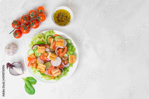 Traditional Middle Eastern vegetarian salad fattoush. Lebanese cuisine recipe. Fresh vegetables, cherry, lettuce, toasted pita bread. White concrete background. Healthy meal, top view. Copy space