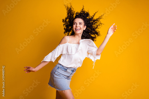 Photo of optimistic flirty brown curly hair girl stand waving friends wear short jeans skirt white top isolated on yellow color background