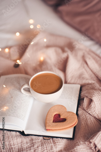 Cup of coffee with tasty cookie on open book close up. Good morning. Breakfast.