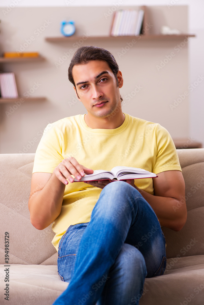 Young male student reading book at home Young male student reading book at home