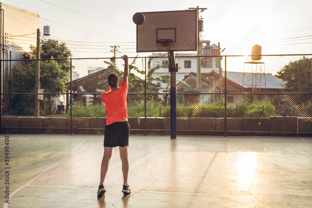 Caucasian young man playing basketball alone