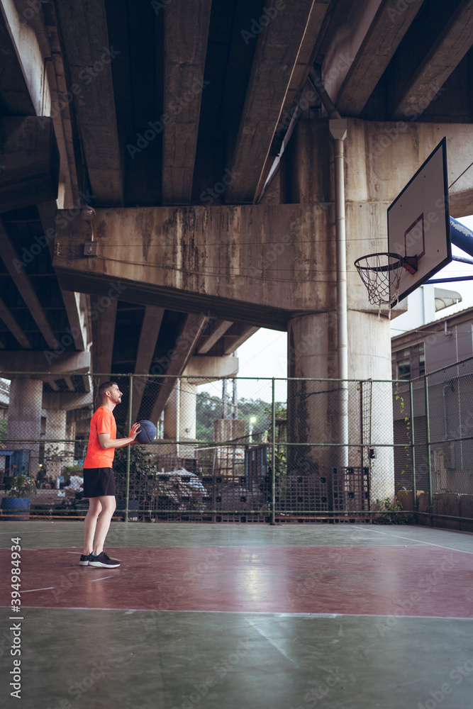 Caucasian young man playing basketball alone