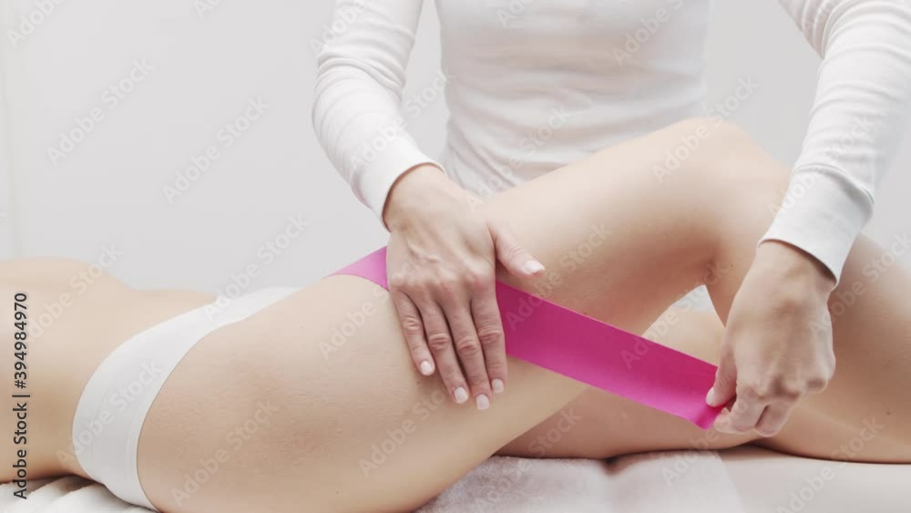 Therapist is applying kinesio tape to female body. Physiotherapy and kinesiology concepts. Therapist is applying kinesio tape to female body. Physiotherapy and kinesiology concepts.