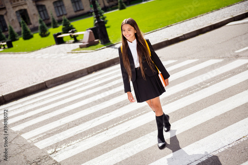 Photo of adorable schoolgirl cross zebra road wear black uniform white shirt socks shoes urban city outdoors