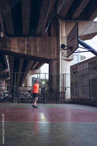 Caucasian young man playing basketball alone