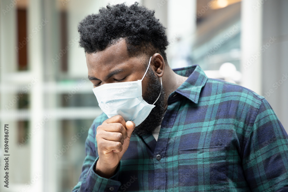 allergic sick black African man coughing with sore throat; concept of African man with allergy, pneumonia, sore throat, influenza, flu, cold, COVID-19 coronavirus, social distancing concept.
