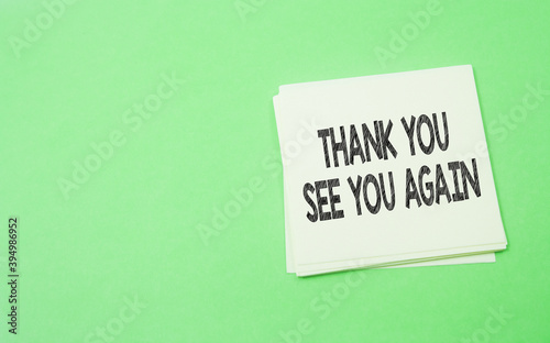 note paper written thank you and see you again over green background