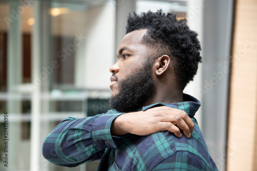 Man scratching suffering from itching shoulder skin; sick African man scratching his skin with allergy, rash, ringworm, tinea problem; skin care, dermatology concept; adult black African man model