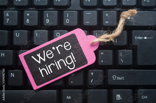 wooden tag written we're hiring over keyboard button background