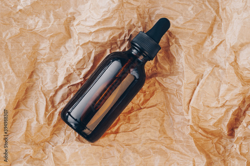 CBD oil bottle, hyaluronic acid tincture on creased cardboard. Serum with collagen and peptides on wrinkled crumpled paper. Beauty product mockup. Anti-age, body care concept. Flatlay, top view photo