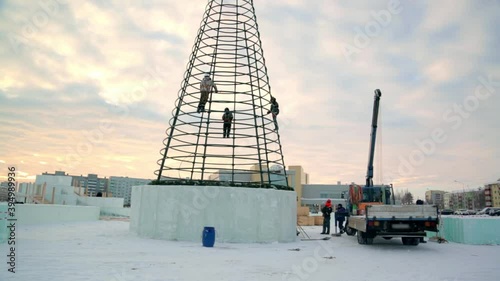 The builders of the ice town enclose the Christmas tree with high ice panels