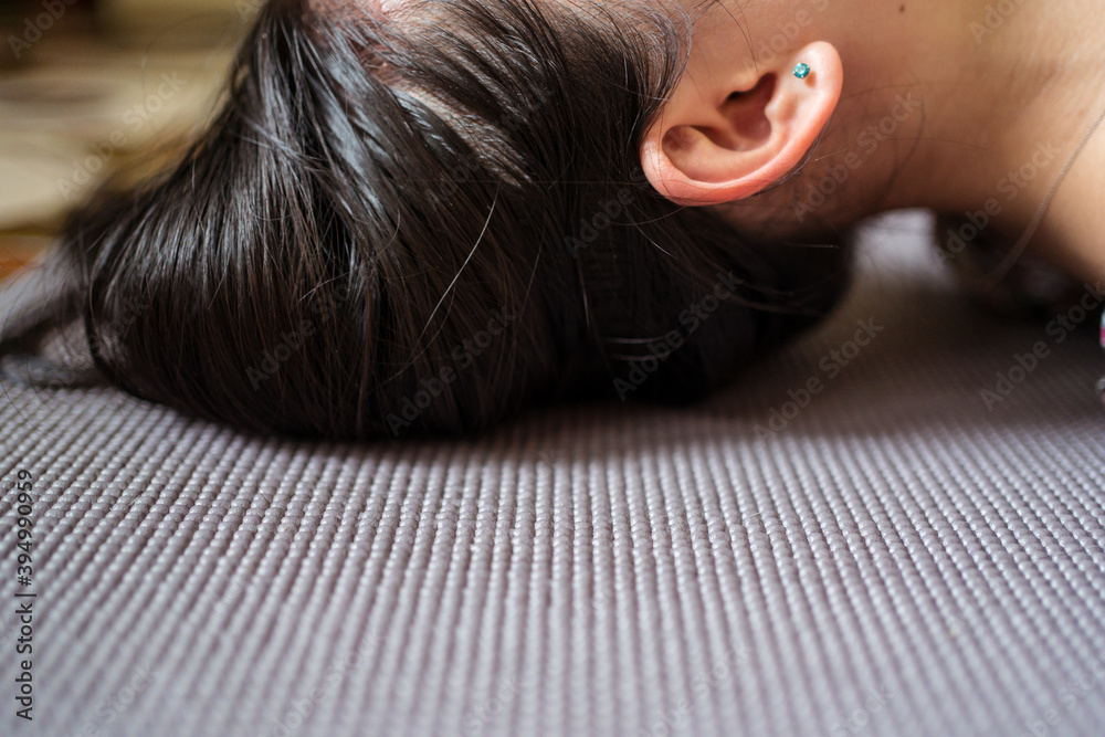 head of unrecognizable woman lying on purple yoga mat