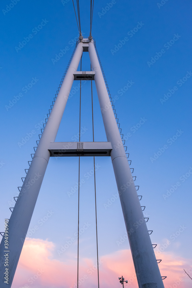Fototapeta premium 晴れた夕焼け空に高くそびえ立つ、つり橋の鉄塔