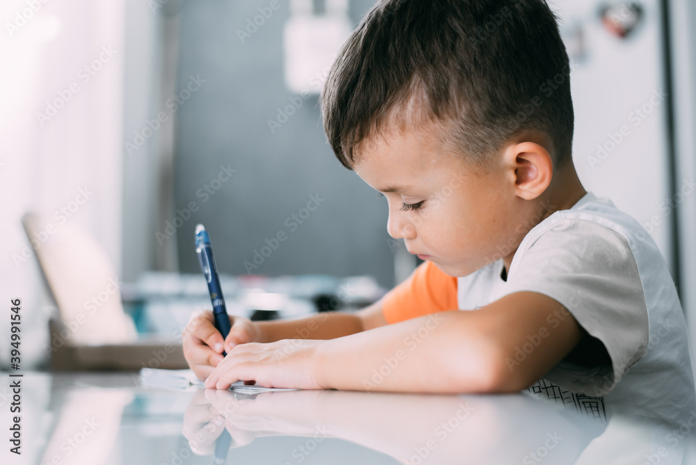 a boy is learning to write the letter K in a notebook preparing for school a boy is learning to write the letter K in a notebook preparing for school