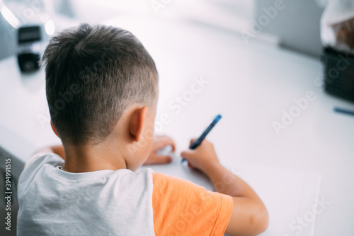 a boy is learning to write the letter K in a notebook preparing for school