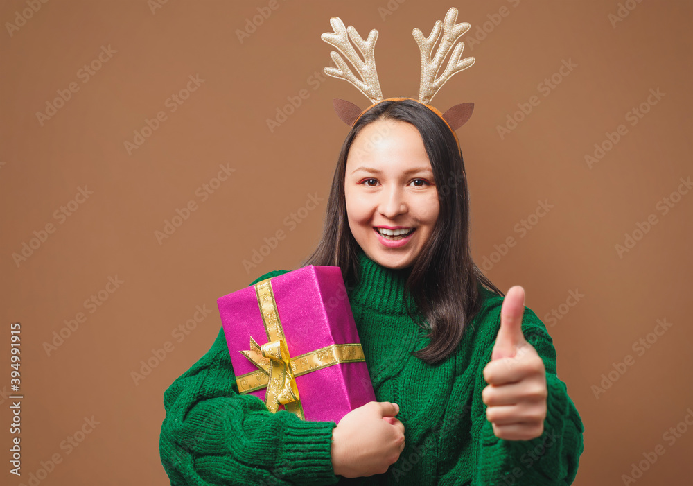 happy young woman in Christmas cap with gift on beige background happy young woman in Christmas cap with gift on beige background