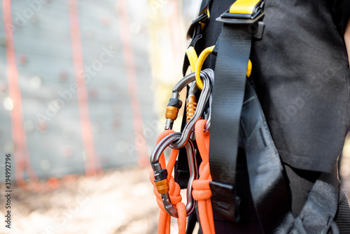 Close-up of safety equipment for climbers weared on the woman with climbing wall on the background