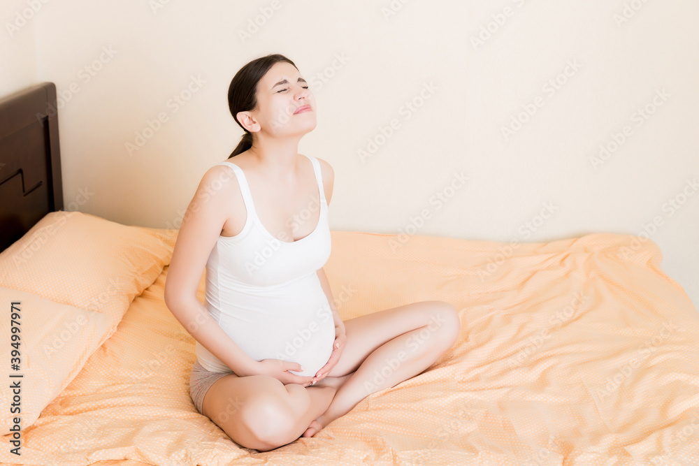 Pregnant Lady Having Massaging Lower belly Sitting On Sofa Indoor. Pregnancy Problems Concept. Maternity healthcare Pregnant Lady Having Massaging Lower belly Sitting On Sofa Indoor. Pregnancy Problems Concept. Maternity healthcare