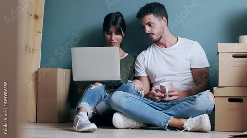 Video of attractive young couple looking decoration ideas with laptop while taking a break sitting on the floor at home. photo