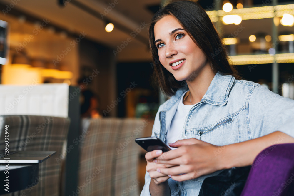 Attractive business woman sits at table in front of laptop and talks on mobile phone, negotiates on the phone. Attractive business woman sits at table in front of laptop and talks on mobile phone, negotiates on the phone.