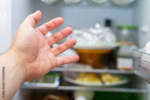 A man's hand reaches for the refrigerator.