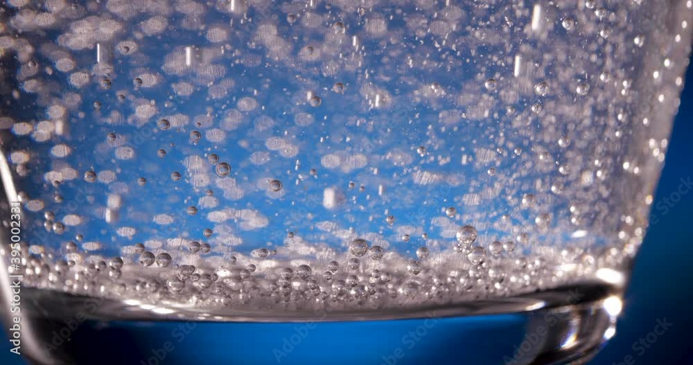 bubbles from dissolved aspirin in water, glass on a blue background bubbles from dissolved aspirin in water, glass on a blue background