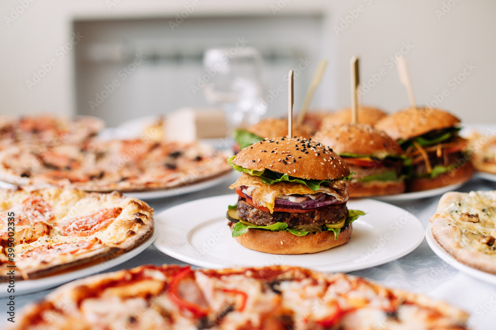 Assorted different pizzas and burgers on the table for tasting or working out the menu, side view