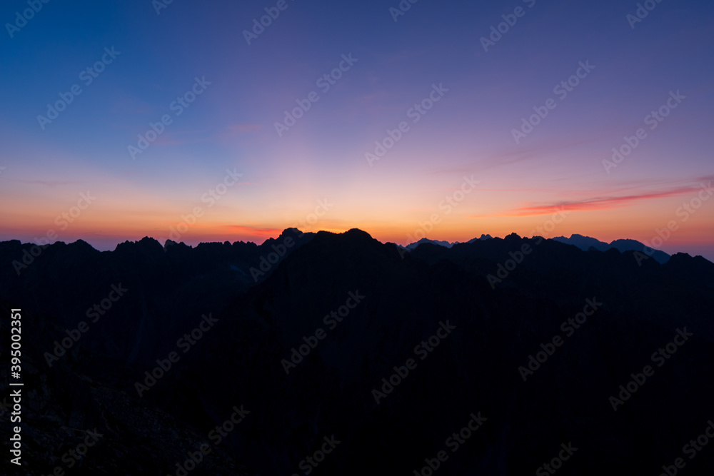 Fototapeta premium Panorama of early sunrise in the mountains. Summer clear sky with rising sun in the high Tatras in Slovakia. Nice scenery on top in Liptov region.