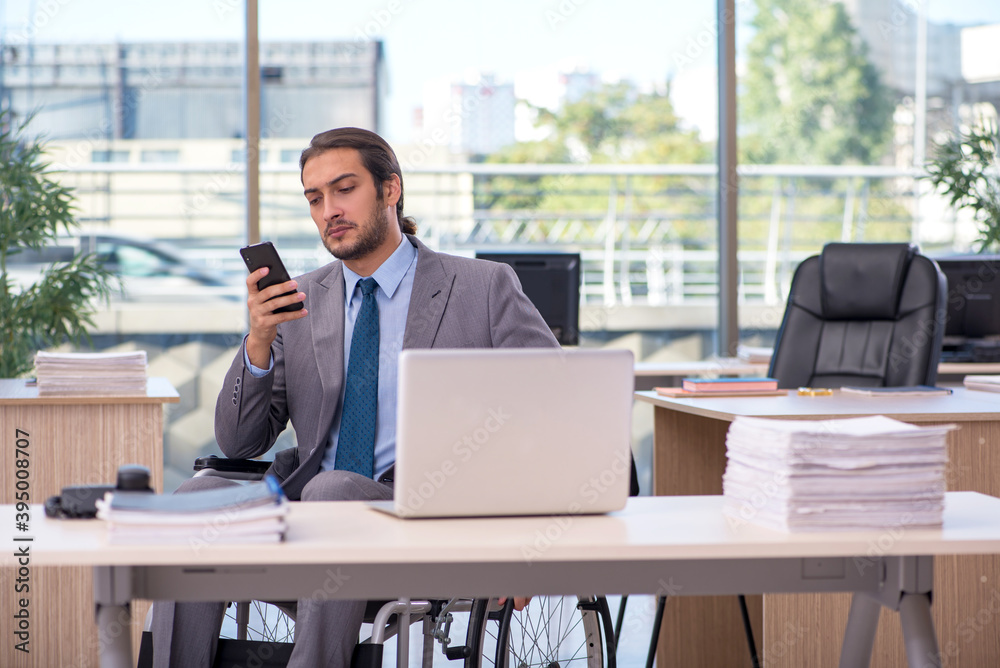Young male employee in wheel-chair working in the office Young male employee in wheel-chair working in the office