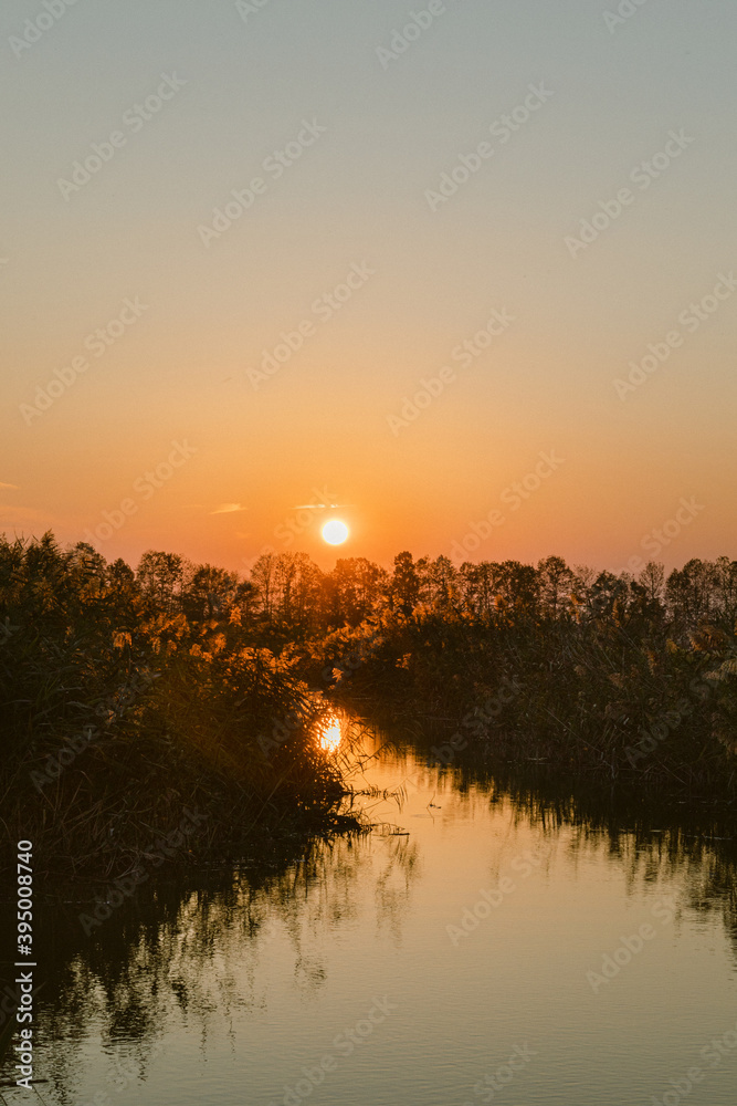 Orange sunset over a river in a swampy region in Italy, Veneto