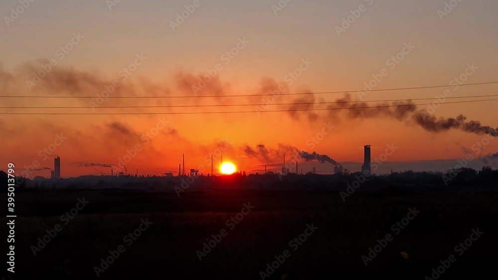 bright orange sunset in an industrial city. dark outlines, silhouettes of smoking factory chimneys against a red sunset background. bright orange sunset in an industrial city. dark outlines, silhouettes of smoking factory chimneys against a red sunset background.