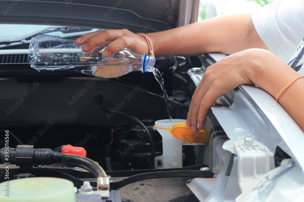 Women refills windshield wiper water on a car. Women refills windshield wiper water on a car.