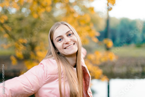 Attractive young woman enjoying her time outside in park with sunset in background. Beautiful young blond woman enjoying. Autumn Portrait of beautiful young woman.
