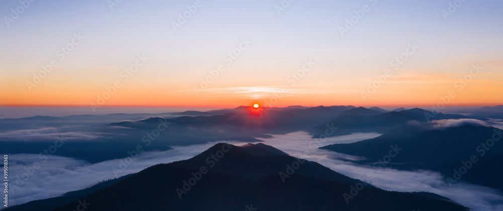 Beautiful panoramic landscape of foggy mountains at sunrise.