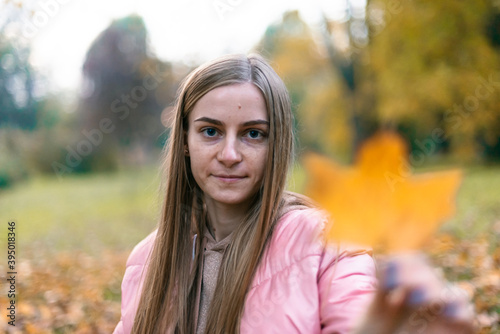 Attractive young woman enjoying her time outside in park with sunset in background. Beautiful young blond woman enjoying. Autumn Portrait of beautiful young woman.
