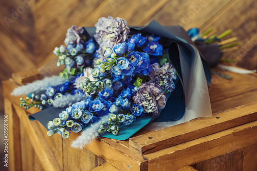 Foto Blue bouquet on a wooden cover in a gray package