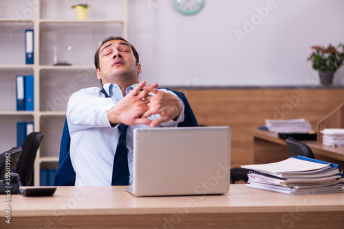 Young male employee stretching at workplace