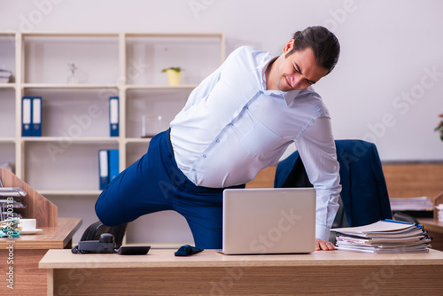 Young male employee doing physical exercises at workplace