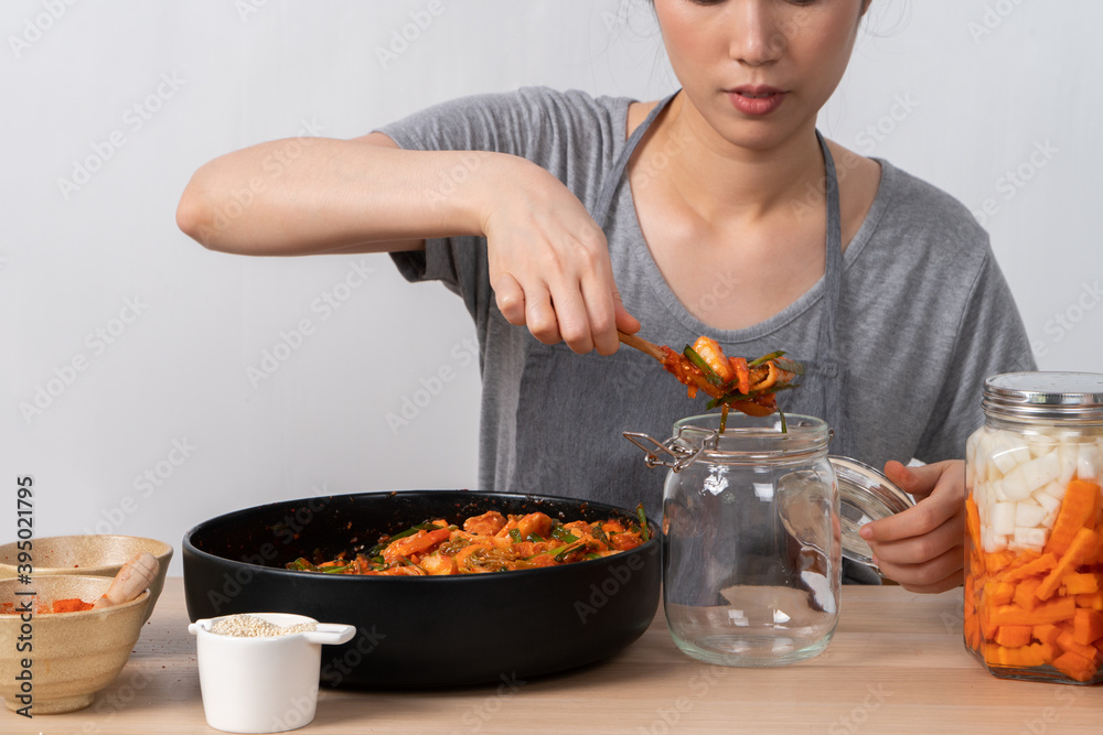 An Asian woman making kimchi and putting kimchi in bottles. After learning to cook at home An Asian woman making kimchi and putting kimchi in bottles. After learning to cook at home