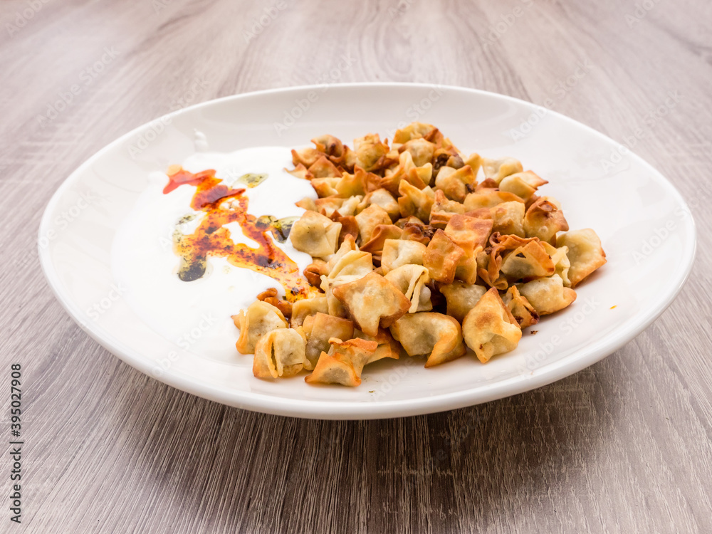 Side view of plate with Turkish Manti with red pepper, tomato sauce, yogurt and mint Side view of plate with Turkish Manti with red pepper, tomato sauce, yogurt and mint