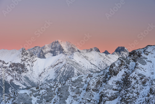 A tourist watches the sunset in the snow-capped winter Tatras