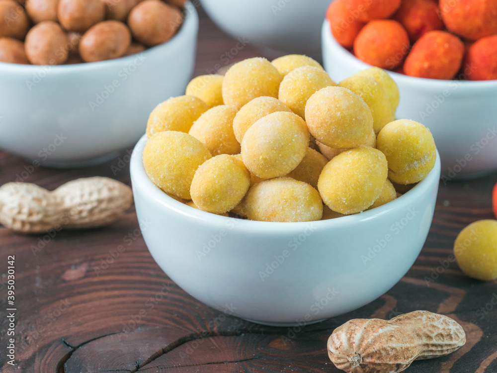 Peanut snack for beer, wine, party bar. Salted peanuts in yellow cheese glaze on brown wooden table. Copy space. Peanut snack for beer, wine, party bar. Salted peanuts in yellow cheese glaze on brown wooden table. Copy space.