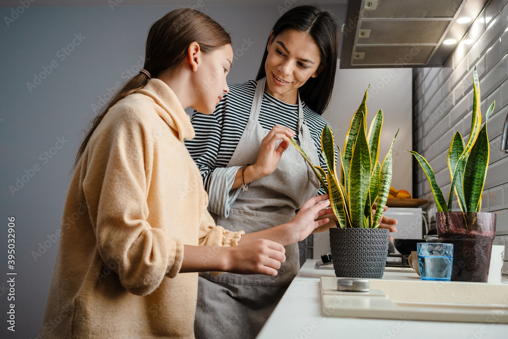 Happy beautiful mother and daughter smiling and watering their plants Happy beautiful mother and daughter smiling and watering their plants
