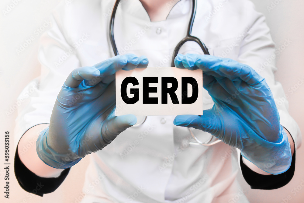 The doctor's blue - gloved hands show the word GERD - . a gloved hand on a white background. Medical concept. the medicine The doctor's blue - gloved hands show the word GERD - . a gloved hand on a white background. Medical concept. the medicine