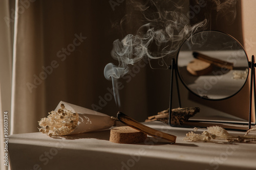  palo santo with jet of smoke, mirror and dried flowers on a neutral background. Abstract trendy picture. Minimalistic wabi sabi style. photo