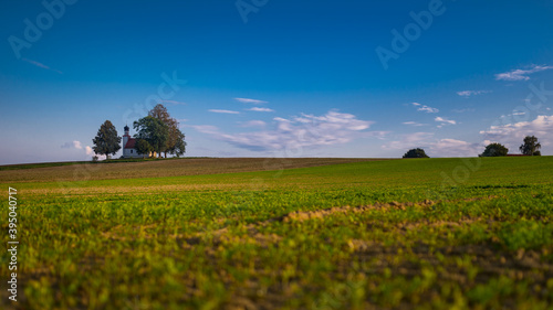 Small chapel on a hill surrounded by old trees and harvested empty fields near Langquaid in lower Bavaria  Germany