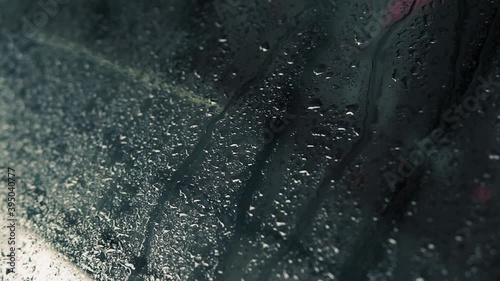 Rain water droplets running down slowly on the car's glass window after the heavy rain. Selective focus.